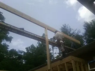 Carpenter setting a ridge beam over a new addition frame — Ice Dam Removal by Roofing Brothers in Aurora