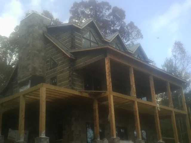Stone chimney and dormers on a large log home with a timber porch in Aurora